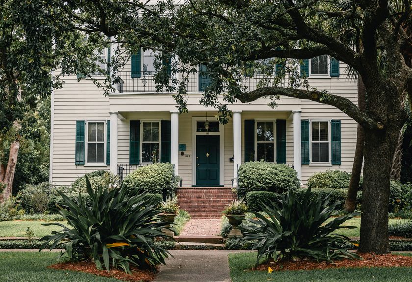 Mature oak spreading over the front yard of a white house